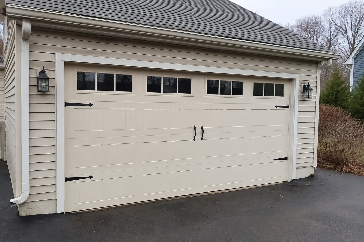 Cream carriage-house-style garage door with dark decorative hardware. — Carriage-House Garage Door Installation, Peterborough
